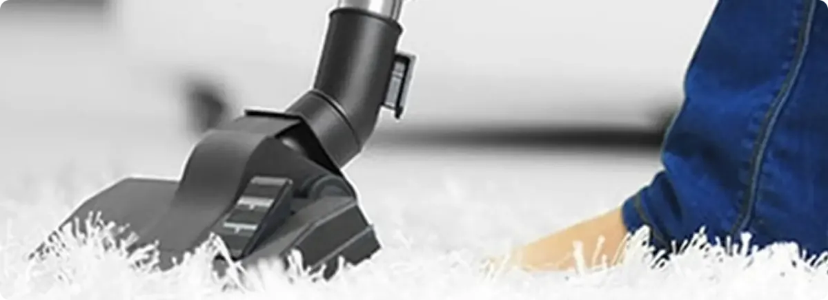 Close-up of a professional vacuuming a white carpet in Theodore.